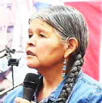 Jean Whitehorse wears her long grey hair in thick braids and has long beaded earrings.